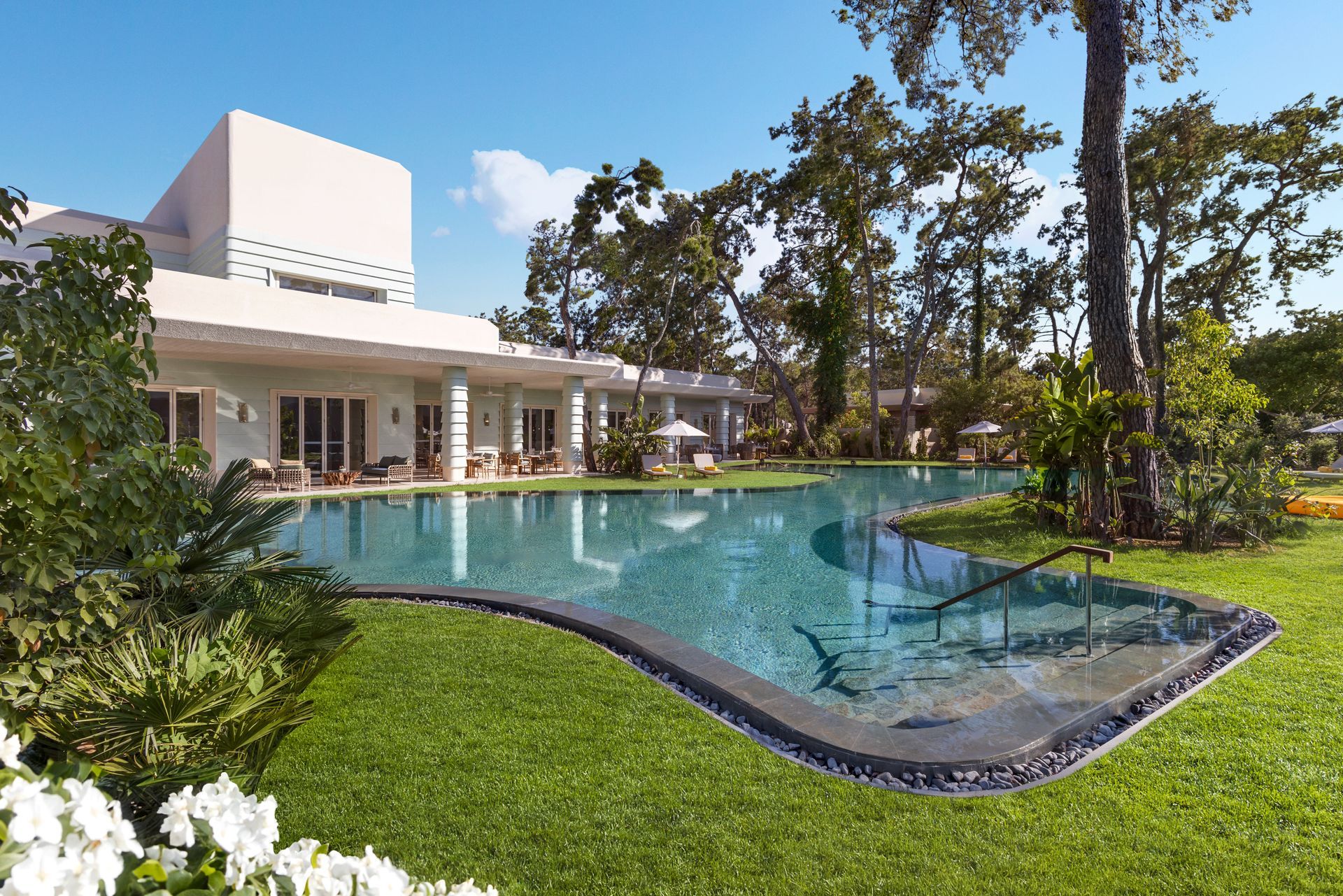 A large white house with a large swimming pool in front of it