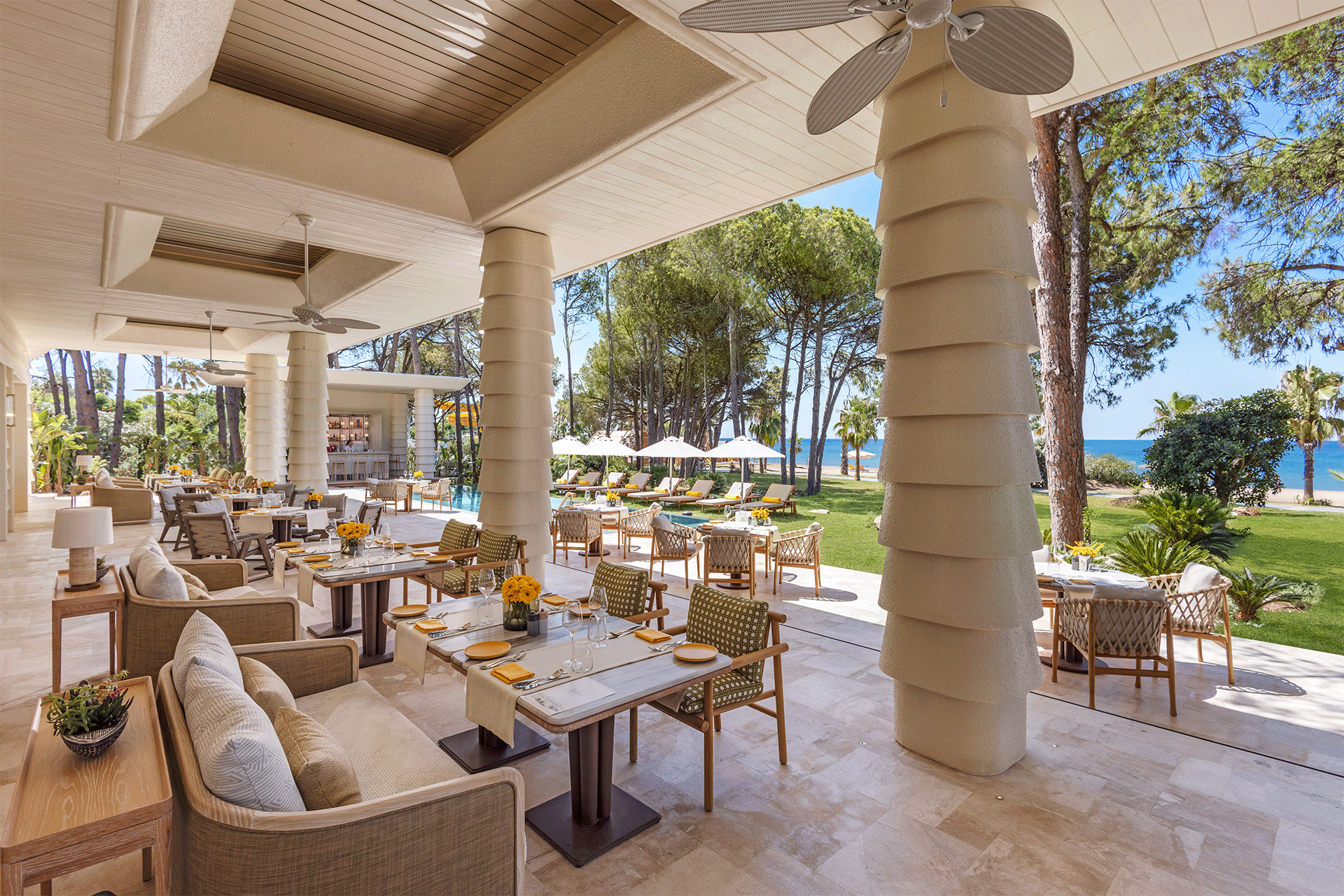 A restaurant with tables and chairs and a view of the ocean.