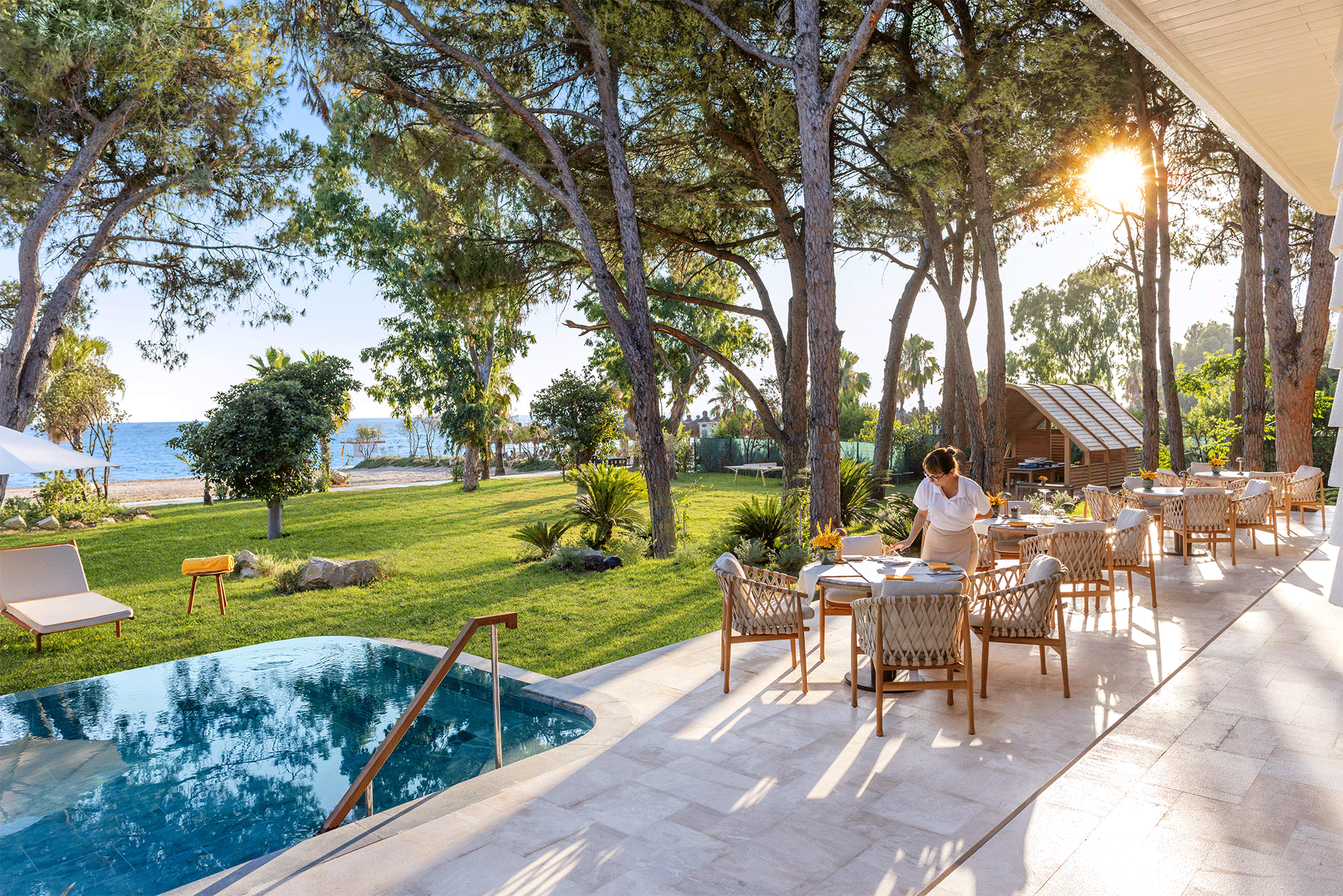 A woman is sitting at a table in front of a swimming pool.