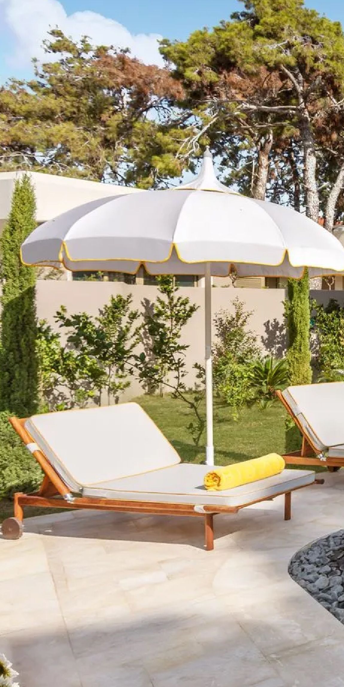 A white umbrella is sitting on a patio next to a pool.