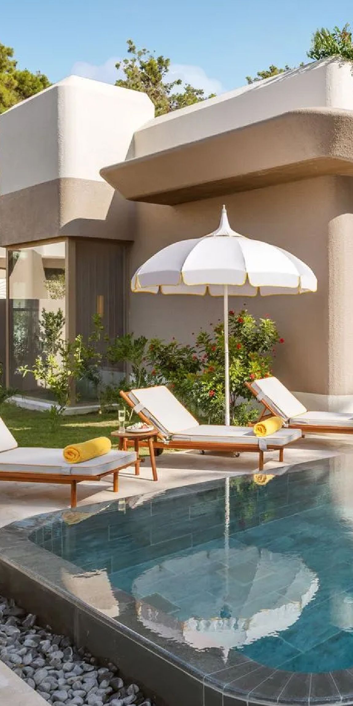A swimming pool with chairs and umbrellas in front of a house.